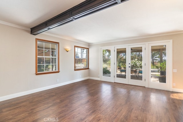 empty room with french doors, ornamental molding, dark wood-style floors, and baseboards