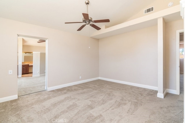empty room featuring light carpet, ceiling fan, lofted ceiling, and baseboards