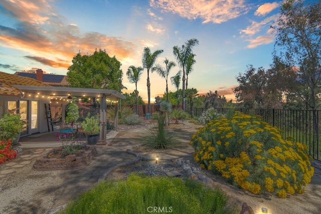 yard at dusk with a fenced backyard and a patio area