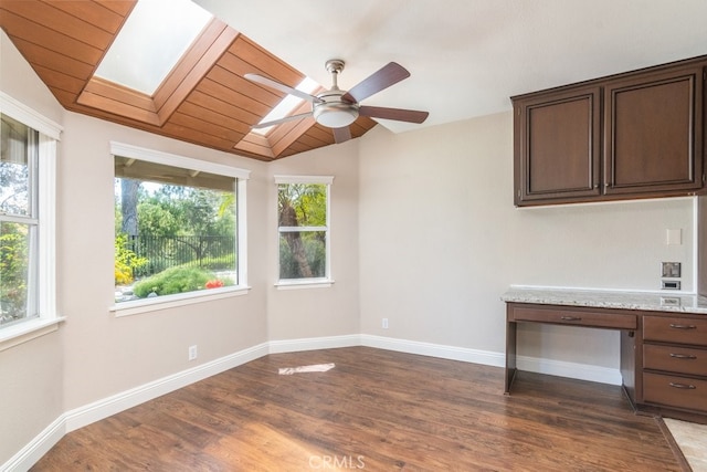 spare room featuring plenty of natural light, a ceiling fan, dark wood finished floors, a skylight, and vaulted ceiling