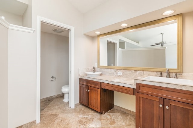 bathroom with a ceiling fan, toilet, and double vanity