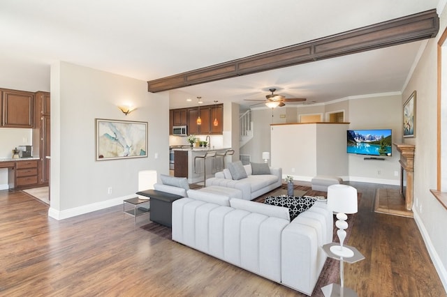 living room featuring wood finished floors, baseboards, ceiling fan, and crown molding