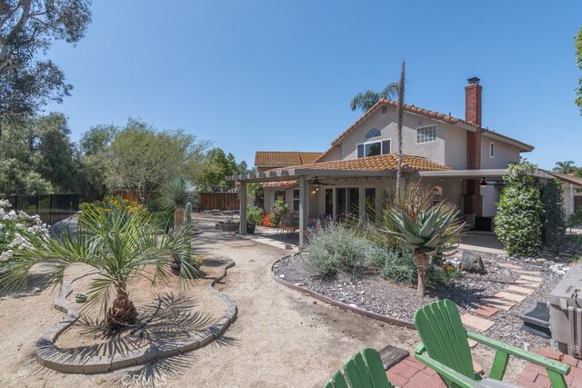 rear view of property featuring a tiled roof, a chimney, a pergola, fence, and a patio area