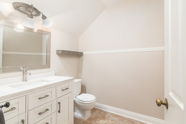 half bathroom featuring vaulted ceiling, toilet, vanity, tile patterned floors, and baseboards
