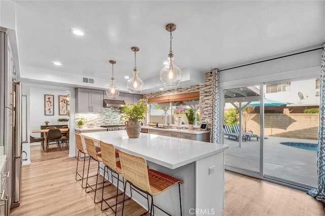 1836 Macinnes Pl, Placentia, CA 92870 - kitchen with tasteful backsplash, light countertops, a breakfast bar, a sink, and light wood-style flooring