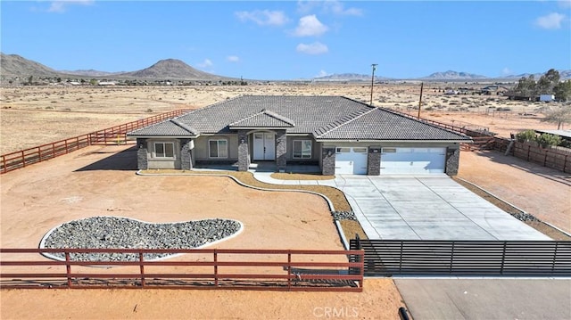 21192 Zuni Rd, Apple Valley, CA 92307 - view of front of house featuring a mountain view, an attached garage, driveway, a tiled roof, and stone siding
