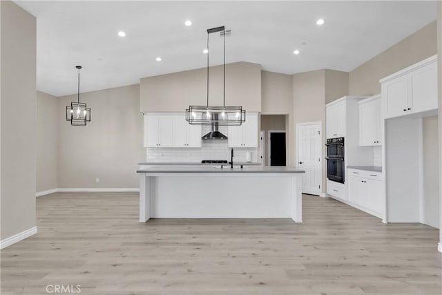 21192 Zuni Rd, Apple Valley, CA 92307 - kitchen with baseboards, tasteful backsplash, white cabinets, an island with sink, and light wood finished floors