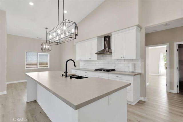 21192 Zuni Rd, Apple Valley, CA 92307 - kitchen with wall chimney range hood, a sink, gas stovetop, a chandelier, and decorative backsplash
