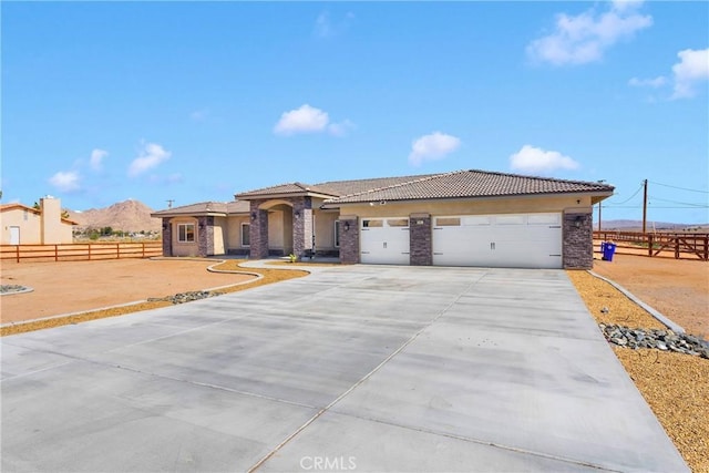 21192 Zuni Rd, Apple Valley, CA 92307 - mediterranean / spanish-style house with driveway, a tile roof, a garage, stucco siding, and stone siding
