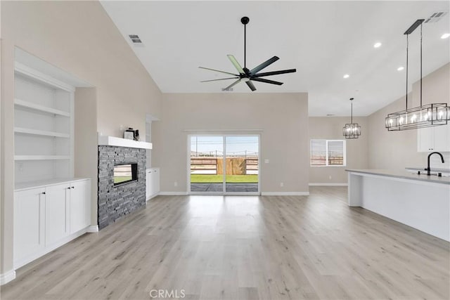 21192 Zuni Rd, Apple Valley, CA 92307 - unfurnished living room with a ceiling fan, a stone fireplace, light wood-type flooring, a chandelier, and high vaulted ceiling