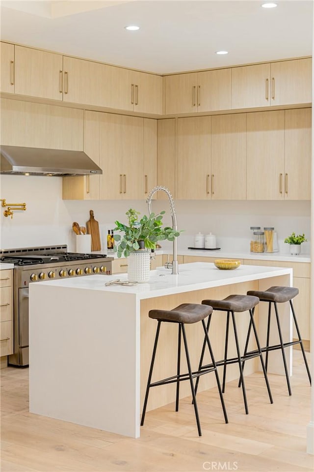 80 Seton Rd, Irvine, CA 92612 - kitchen featuring light brown cabinets, stainless steel range with gas cooktop, under cabinet range hood, an island with sink, and a breakfast bar area