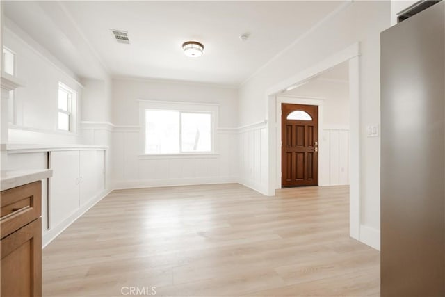 247 S Benton Way, Los Angeles, CA 90057 - unfurnished dining area with light wood-style floors, wainscoting, and a decorative wall