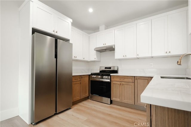 247 S Benton Way, Los Angeles, CA 90057 - kitchen featuring stainless steel appliances, under cabinet range hood, a sink, light wood finished floors, and white cabinetry