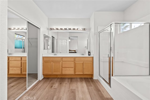 9011 Honeysuckle Ave, Hesperia, CA 92344 - bathroom with a stall shower, wood finished floors, double vanity, a bath, and plenty of natural light