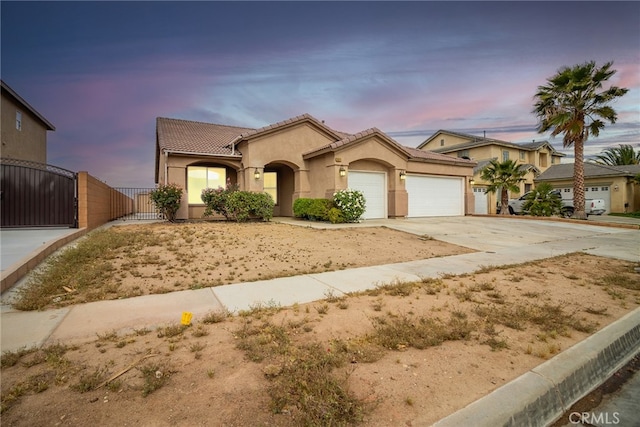 9011 Honeysuckle Ave, Hesperia, CA 92344 - mediterranean / spanish-style house featuring a gate, an attached garage, concrete driveway, a tile roof, and stucco siding