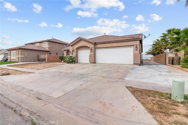 9011 Honeysuckle Ave, Hesperia, CA 92344 - mediterranean / spanish house with a gate, driveway, a tile roof, stucco siding, and a garage