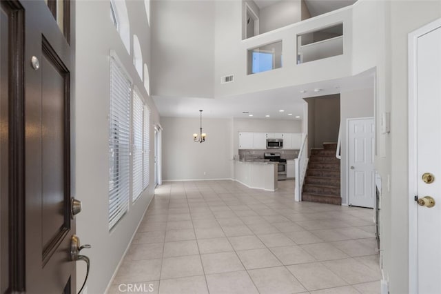 170 Valley View Ter, Mission Viejo, CA 92692 - unfurnished living room with a towering ceiling, baseboards, a chandelier, light tile patterned flooring, and stairs