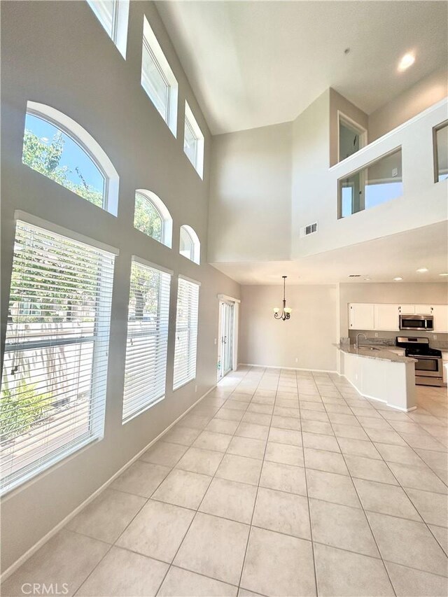 170 Valley View Ter, Mission Viejo, CA 92692 - unfurnished living room featuring light tile patterned floors, a high ceiling, baseboards, a chandelier, and a sink