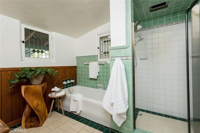 bathroom with a wainscoted wall, tile patterned floors, a shower stall, and a bath