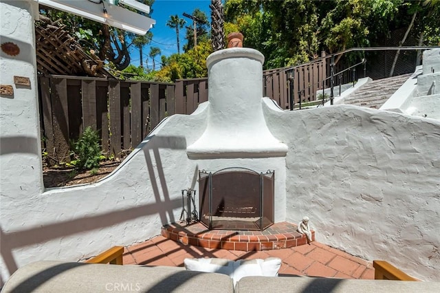 detailed view of fence and an outdoor brick fireplace