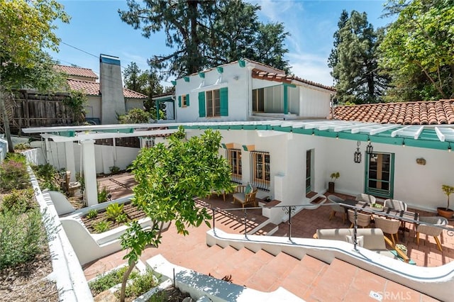 rear view of house with stucco siding, a tile roof, fence, and a patio area