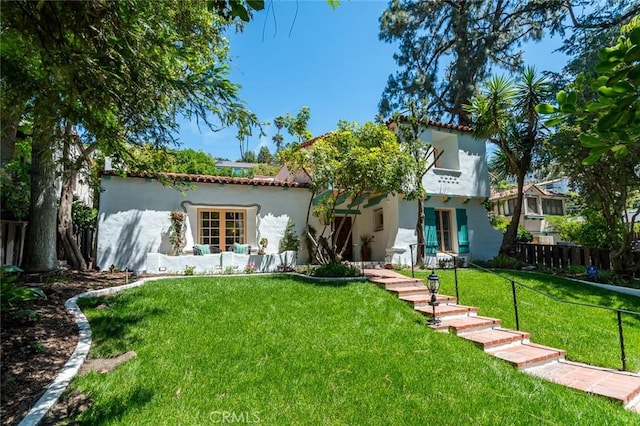 back of house featuring stucco siding and a tile roof