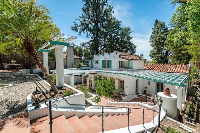 rear view of house featuring a patio, a tile roof, fence, and stucco siding