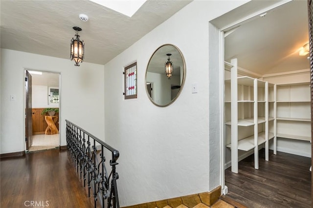 hallway with wood finished floors, baseboards, and a skylight