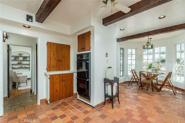 kitchen with beam ceiling, tile countertops, baseboards, brown cabinets, and a ceiling fan