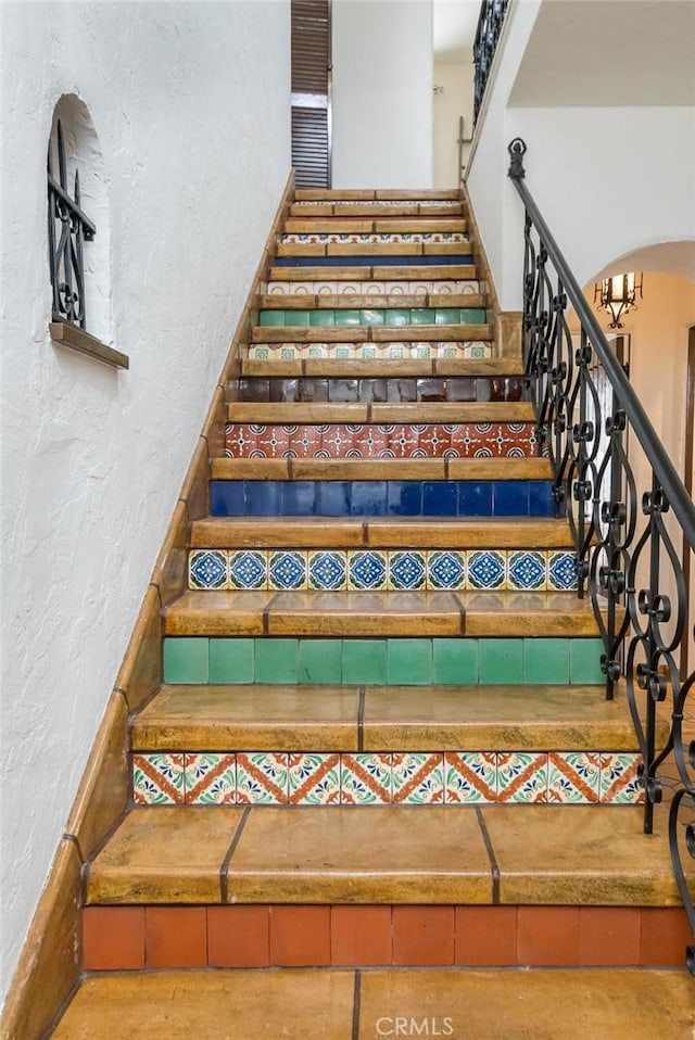 stairs featuring a textured wall and arched walkways