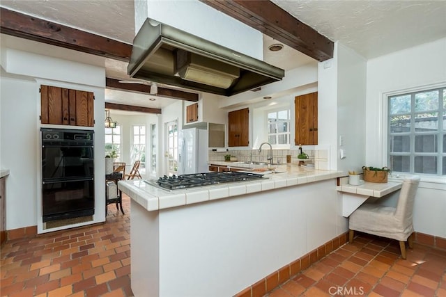 kitchen with stainless steel gas stovetop, tile countertops, decorative backsplash, beam ceiling, and extractor fan