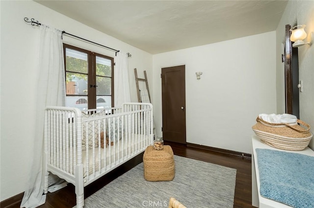bedroom with wood finished floors, baseboards, and a crib