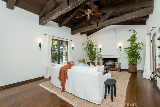 living area featuring wooden ceiling, a large fireplace, hardwood / wood-style floors, beamed ceiling, and ceiling fan