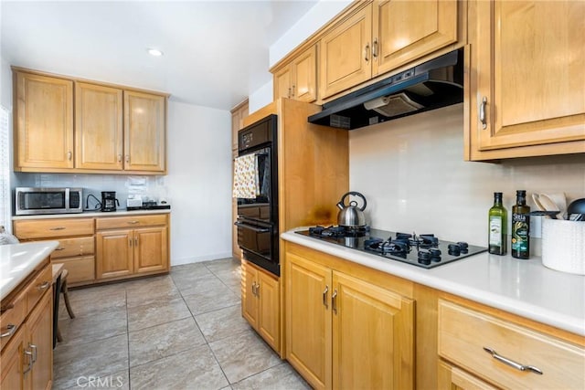 14027 Wyandotte St, Van Nuys, CA 91405 - kitchen featuring under cabinet range hood, black appliances, a warming drawer, light countertops, and tasteful backsplash