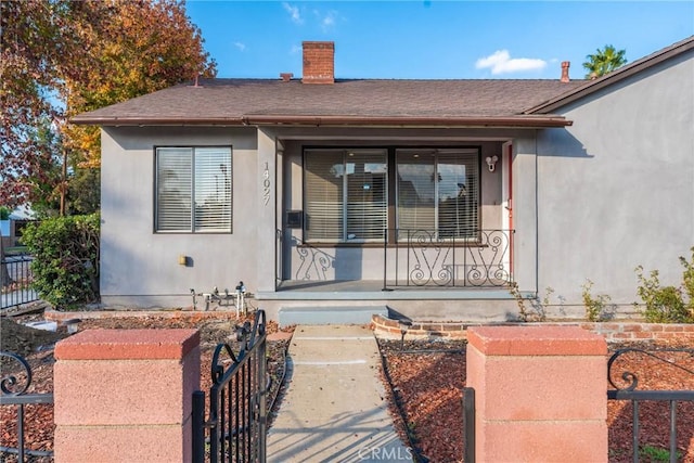 14027 Wyandotte St, Van Nuys, CA 91405 - view of exterior entry with fence, a porch, a chimney, and a gate