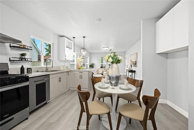 2461 Saint Pierre Ave, Altadena, CA 91001 - kitchen featuring stainless steel range with gas cooktop, light wood finished floors, a sink, light countertops, and white cabinets