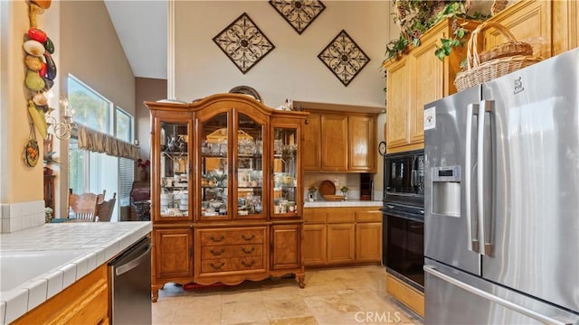 1551 Dominguez Ranch Rd, Corona, CA 92882 - kitchen with black appliances, tile counters, high vaulted ceiling, tasteful backsplash, and brown cabinets