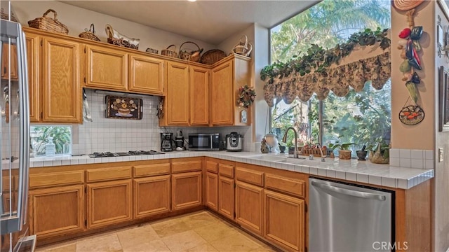 1551 Dominguez Ranch Rd, Corona, CA 92882 - kitchen with stainless steel appliances, decorative backsplash, tile countertops, and brown cabinets
