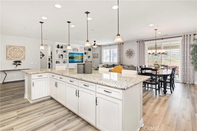 25303 Water Wheel Ct, Menifee, CA 92584 - kitchen with light wood-type flooring, open floor plan, recessed lighting, white cabinetry, and light stone counters