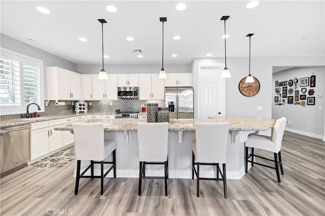 25303 Water Wheel Ct, Menifee, CA 92584 - kitchen featuring stainless steel appliances, light wood-style floors, a spacious island, decorative backsplash, and a sink