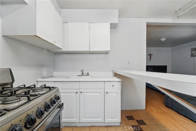 12737 Cometa Ave, San Fernando, CA 91340 - kitchen with range with gas stovetop, a sink, light countertops, and white cabinets