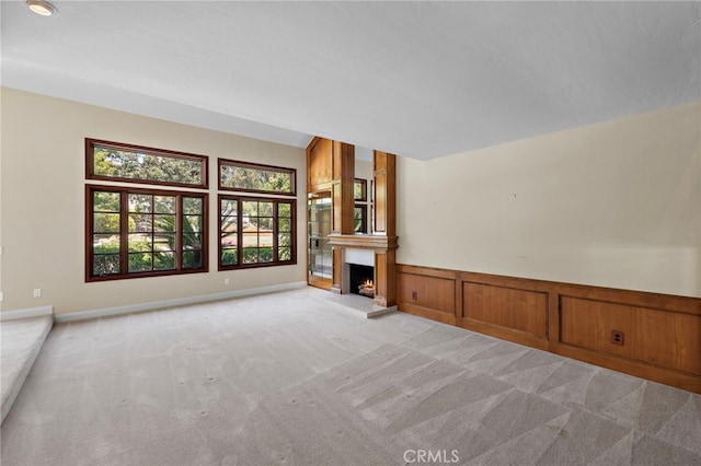 26021 Flintlock Ln, Laguna Hills, CA 92653 - unfurnished living room with light colored carpet, a lit fireplace, and a wainscoted wall