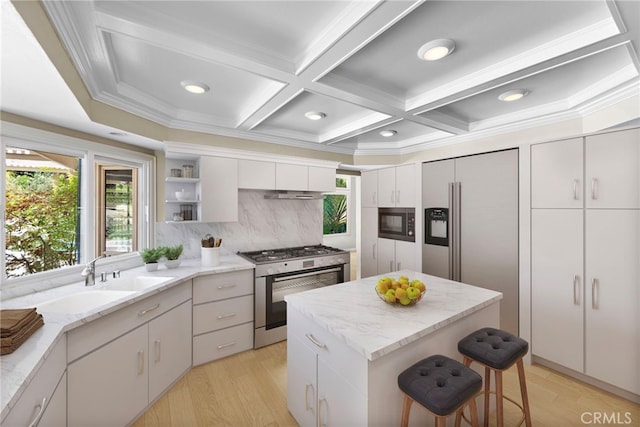 26021 Flintlock Ln, Laguna Hills, CA 92653 - kitchen with appliances with stainless steel finishes, a kitchen bar, backsplash, coffered ceiling, and light wood-type flooring