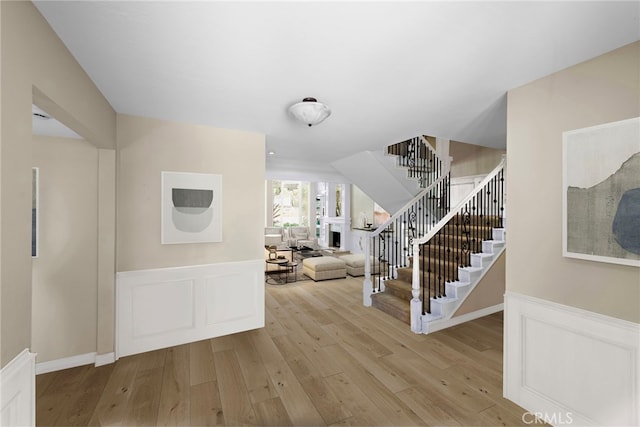 26021 Flintlock Ln, Laguna Hills, CA 92653 - entryway with stairway, light wood-type flooring, a wainscoted wall, a decorative wall, and a fireplace