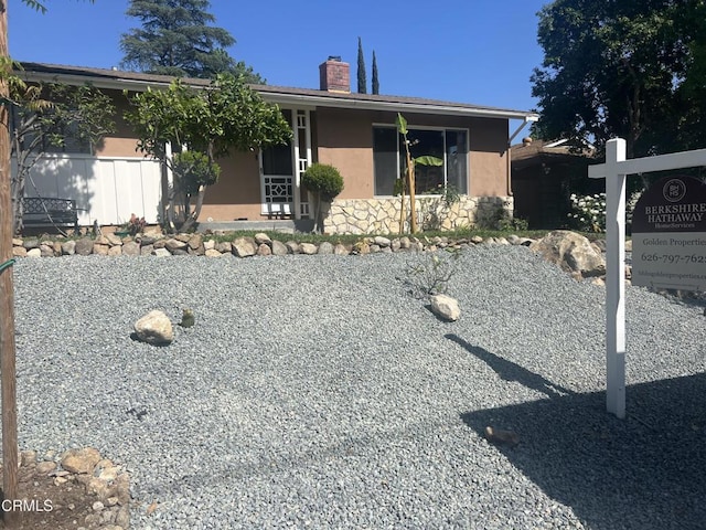 single story home with a chimney, stucco siding, and stone siding