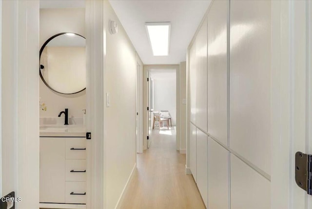 10720 Ohio Ave Unit 5, Los Angeles, CA 90024 - hallway with a sink, light wood finished floors, and baseboards