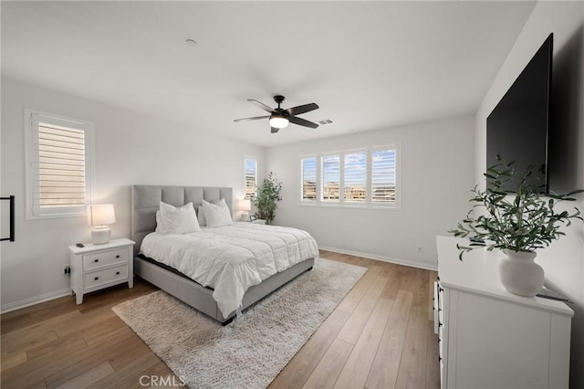 bedroom with light wood-style floors, baseboards, and a ceiling fan