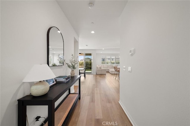 hallway featuring light wood-type flooring, recessed lighting, and baseboards