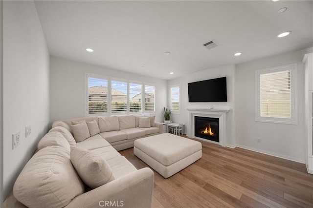 living room with light wood-style floors, recessed lighting, a glass covered fireplace, and baseboards