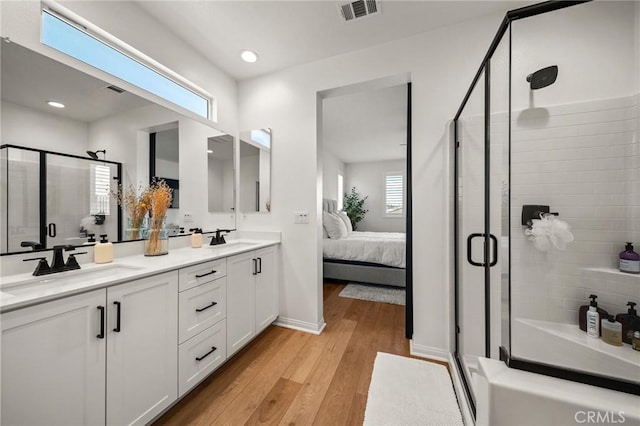 bathroom featuring ensuite bath, a stall shower, wood finished floors, double vanity, and recessed lighting